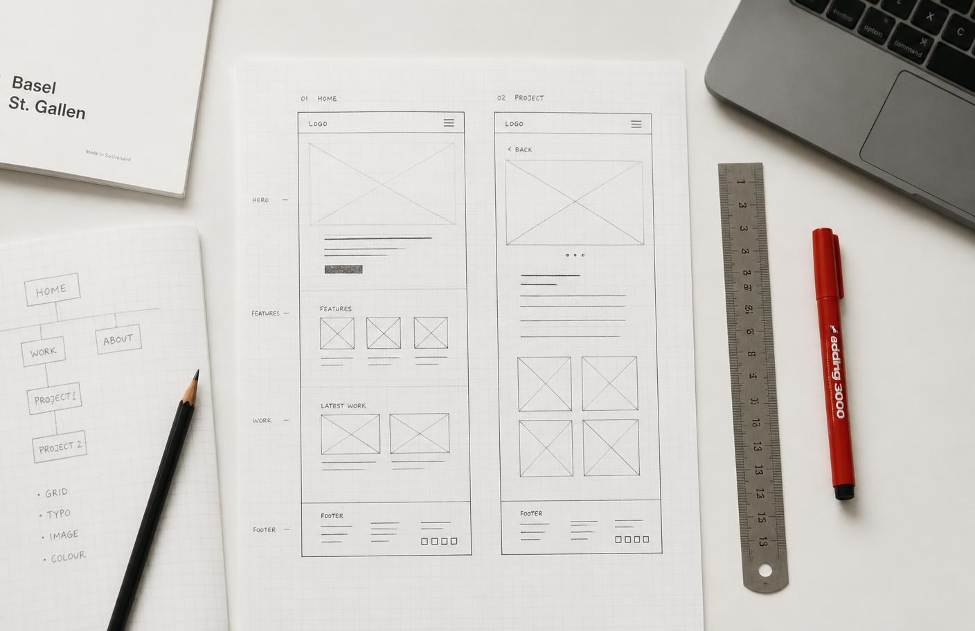 Planning documents, wireframes and drawing tools arranged on a work surface